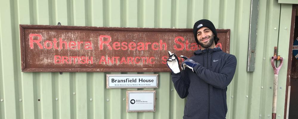 Masterstudent Salar Karam står framför forskningsstation i Antarktis. 