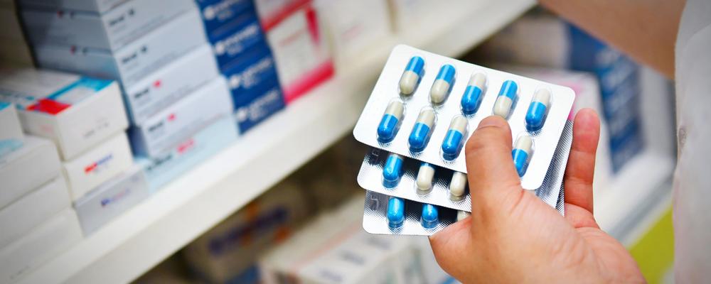 En apotekares händer håller i antibiotikapiller.