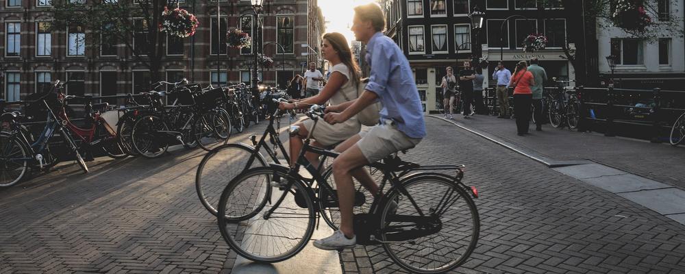 Två personer som cyklar genom Amsterdam.