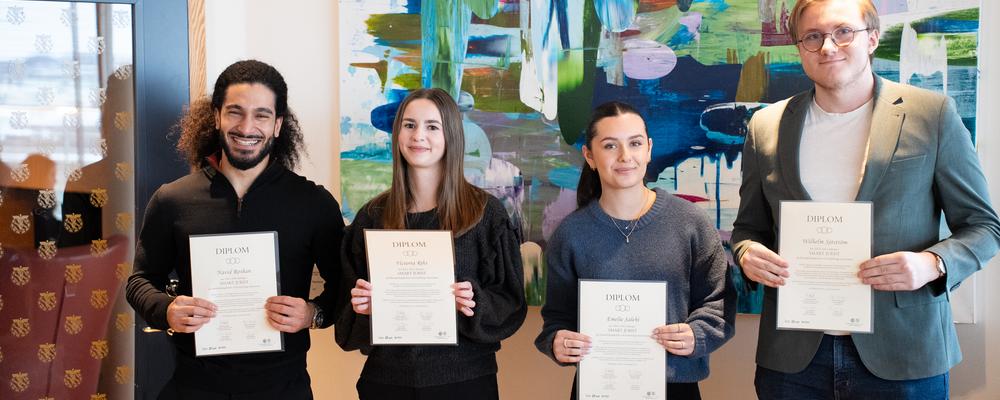 Four students with diplomas