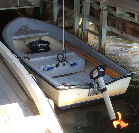 Båt med elektrisk utombordsmotor i aktern, förtöjd i båthus