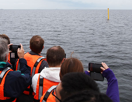Gul gränsboj på havsytan som studerande fotograferar