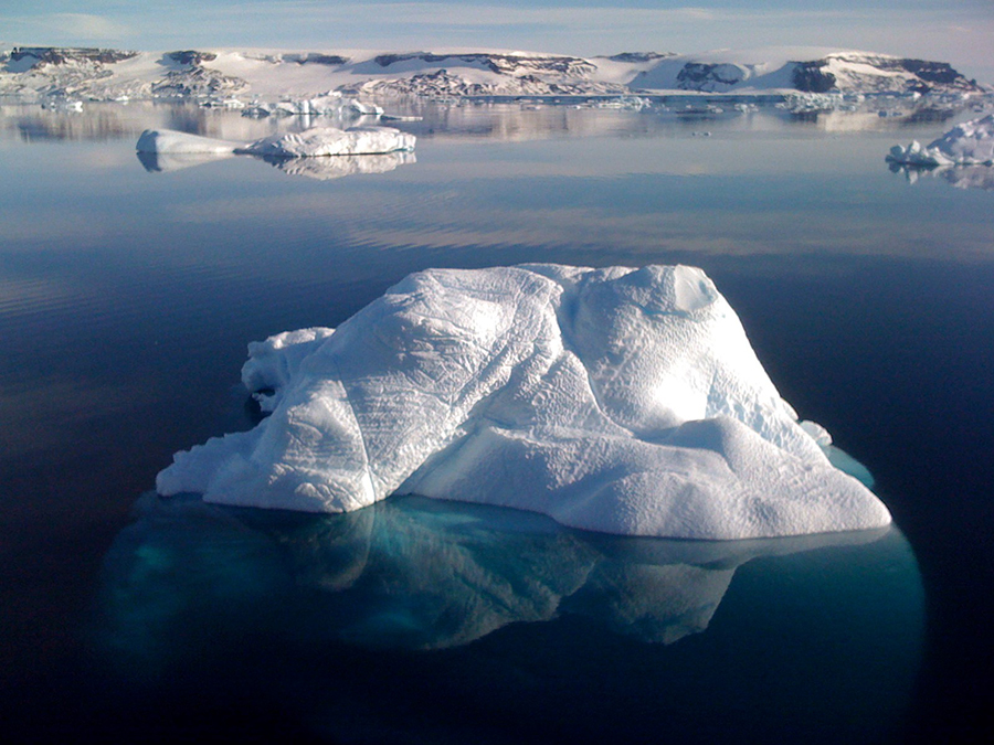 Små isflak och snötäckta kullar omgärdat av kristallklart vatten