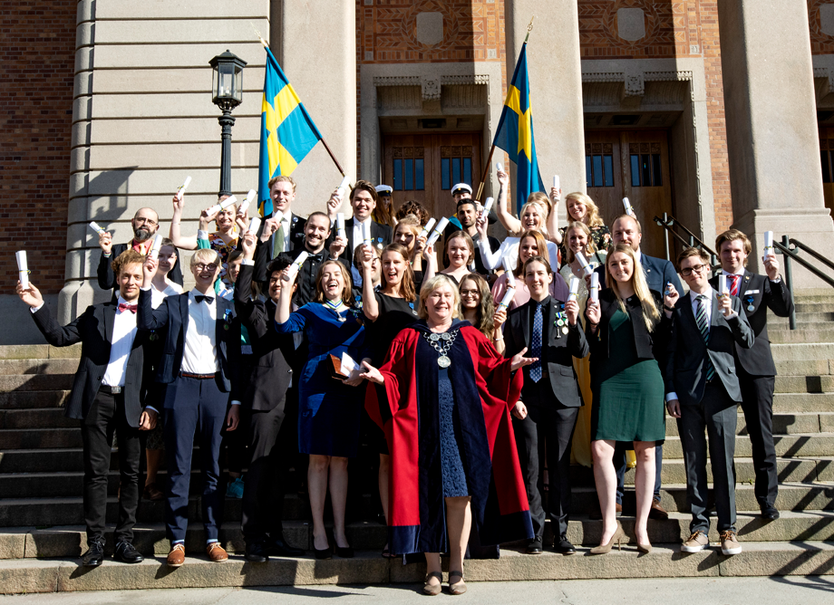 Deltagarna på diplomeringsceremonin poserar framför universitetets huvudbyggnad tillsammans med rektor Eva Wiberg