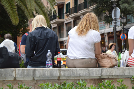 The picture shows some teenagers sitting outdoors, you don't see their faces, and one in the group has obesity.