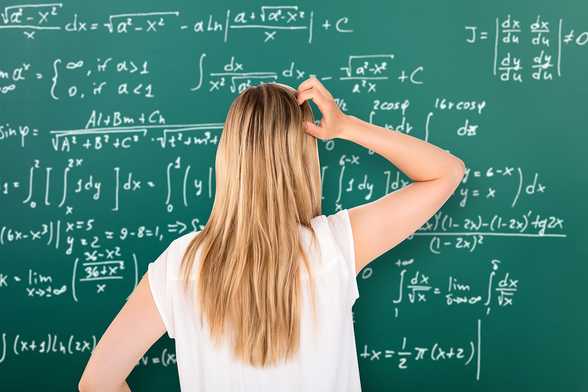 Student kliar sig i huvudet framför tavla med komplicerade matematikformler.