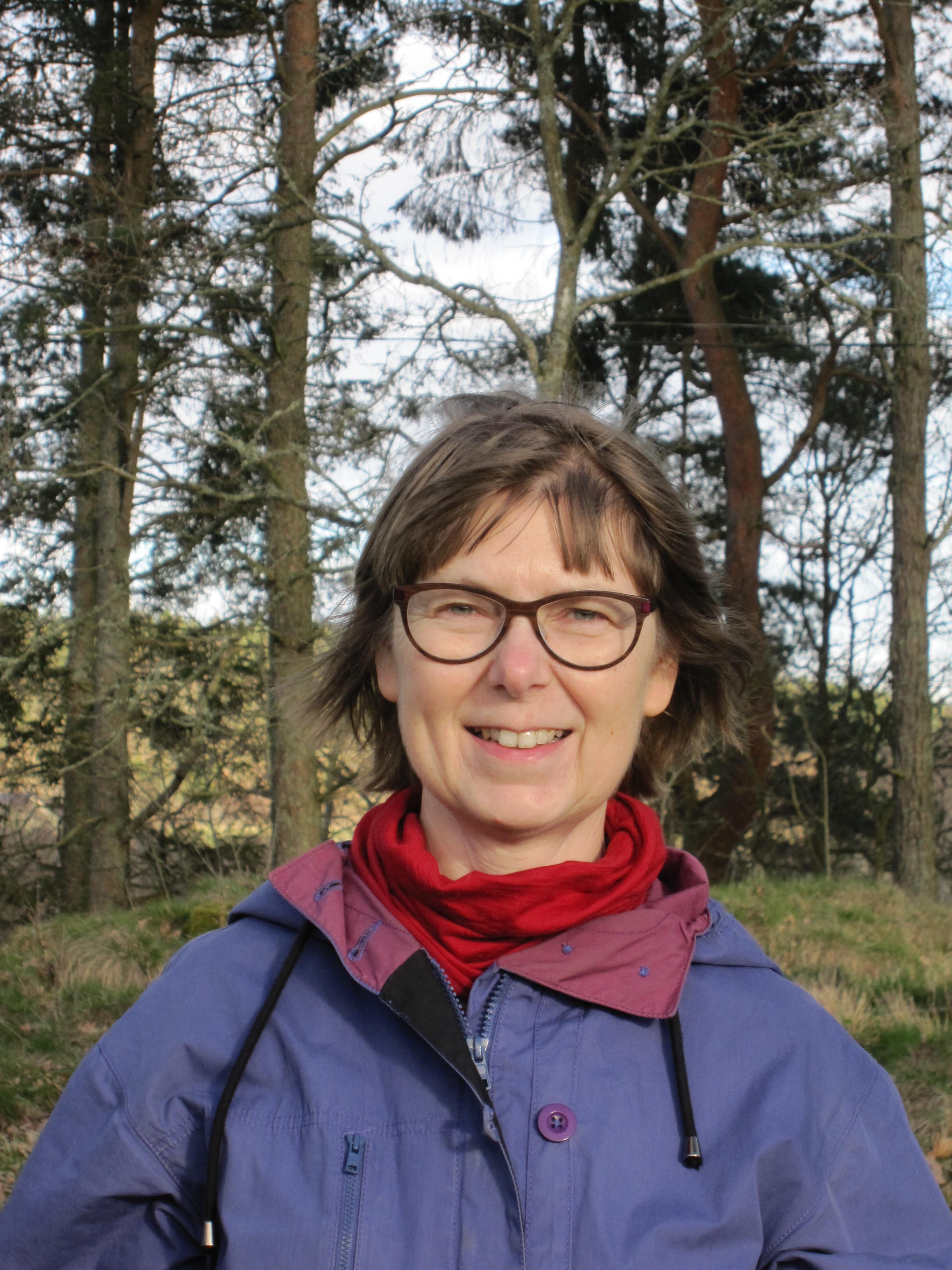 Porträttbild på Åsa Kasimir. Bilden är tagen i skogen. 