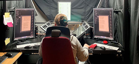 Bild av kvinna i kontorsstol som arbetar med flera skärmar framför sig