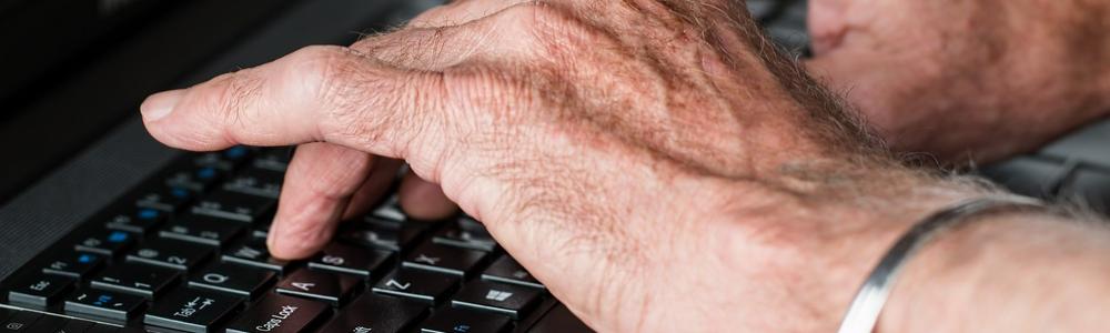 äldre händer skriver på laptop