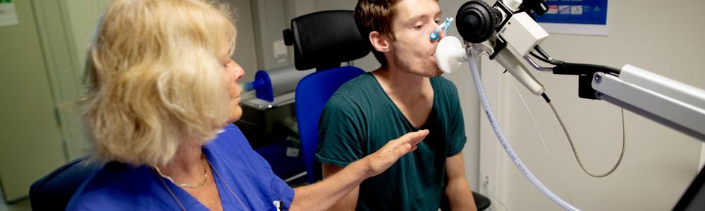 A patient is breathing through a nozzle while participating in a lung function test.