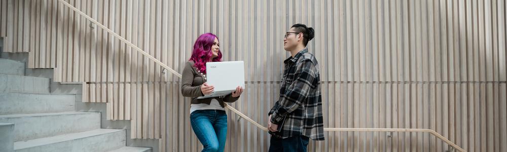 Två studenter står vid en vägg på Humanisten och diskuterar
