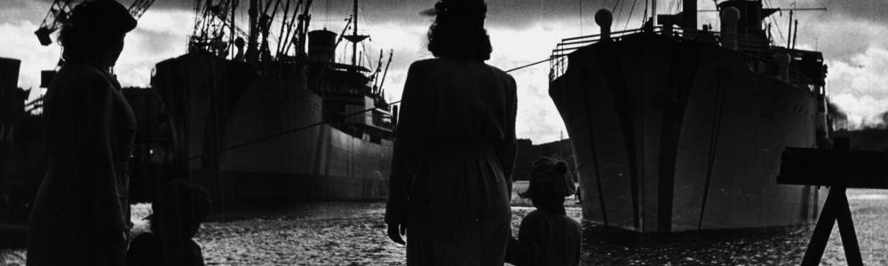 Svartvit, hamnen i göteborg 1950tal, en kvinna och barn blickar ut över några båtar.