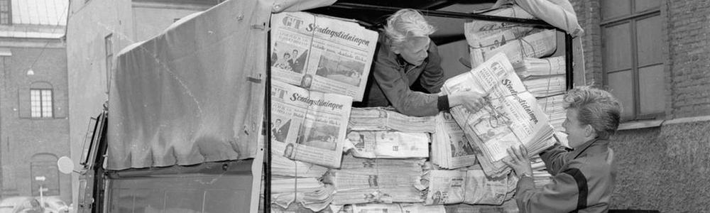 Två pojkar lastar av tidningar från en lastbil. 1950tal.