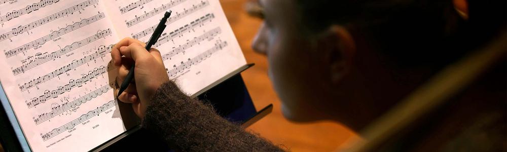 Cello student taking notes on music sheet