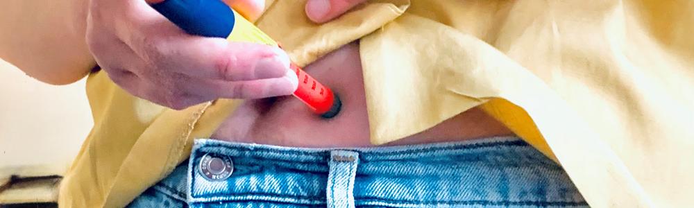 young adult injects insulin in her stomach