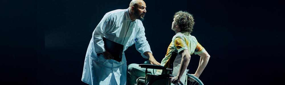 A medical doctor talking to a person in a wheelchair.