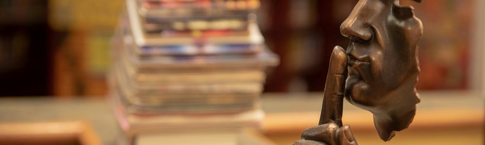 Skulptur med fingret framför munnen.