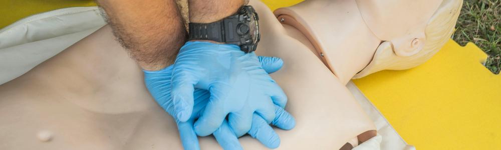Docka får simulerad hjärt- och lungräddning av handskbeklädda händer