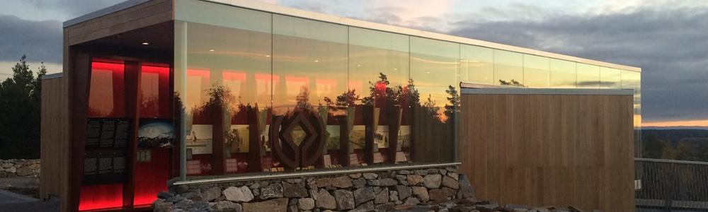 Ett hus med stora fönster- istället för väggar fotograferat i kvällsljus