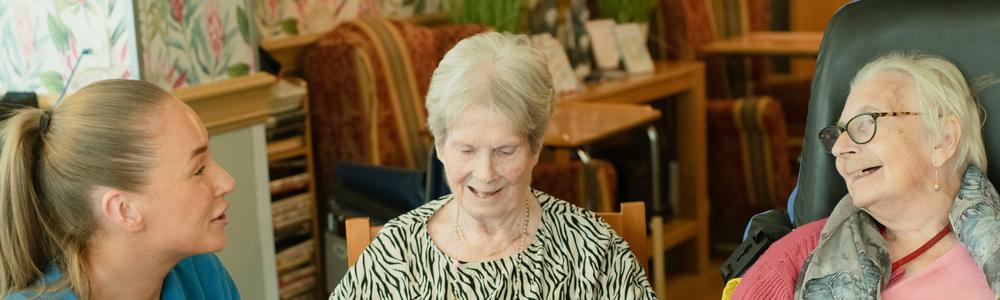 två äldre kvinnor pratar med en personal på ett demensboende 