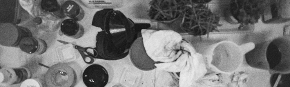 A number of objects, scissors, tape, plants, on a table