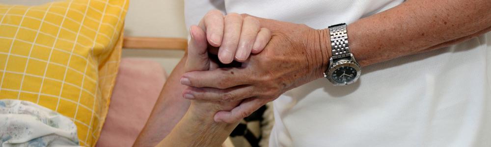 En sköterska håller en äldre kvinnas arm