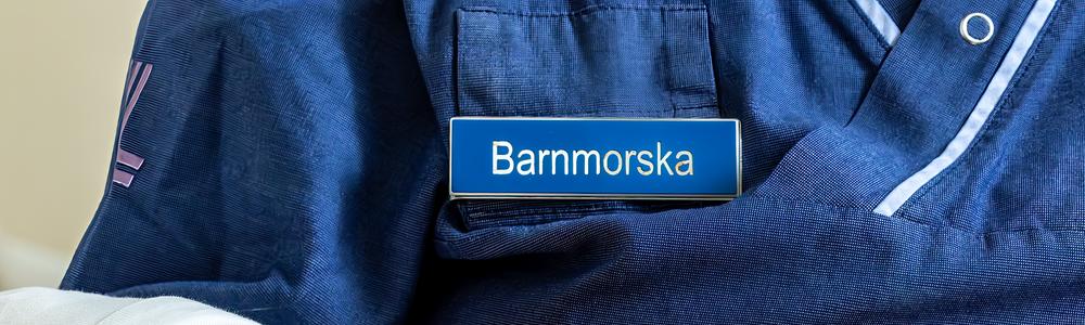 barnmorska i arbetskläder håller en nyfödd 