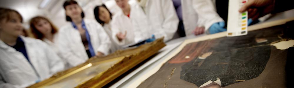 Studenter tittar på tavlor, foto.