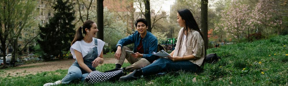 tre studenter sitter på gräsmatta
