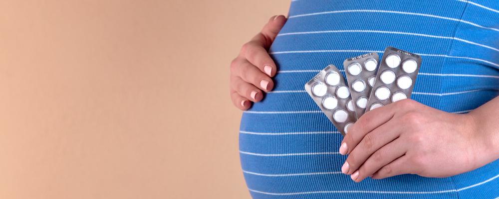 Gravid kvinna med tablettkartor i handen