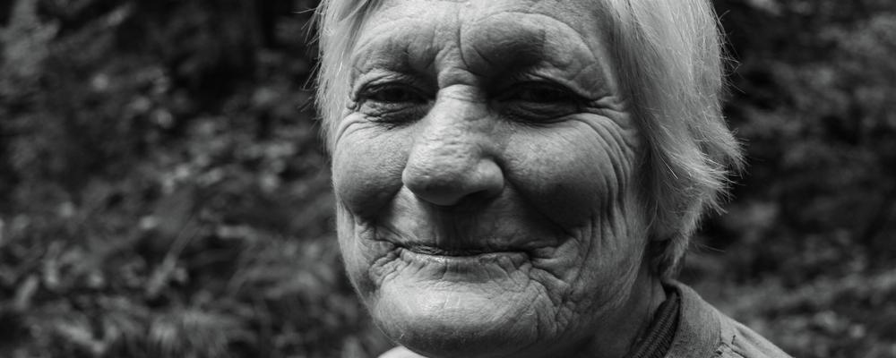 En gammal kvinna ler in i kameran 