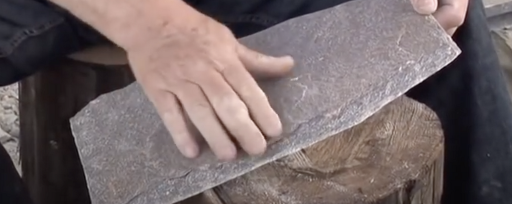 Bilden visar en hand mot en skifferplatta