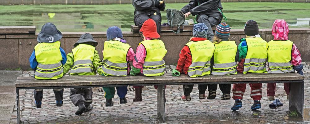 Preschool children sitting on a bench.