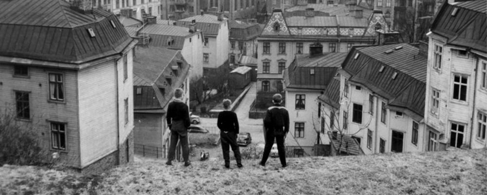 Tre pojkar blickar ut över ett berg