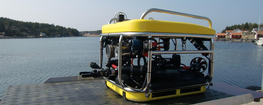 A yellow-coloured remotely operated vehicle on a pier with sea in the background
