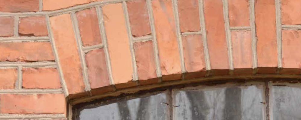 Bilden visar ett murat valv av rött tegel ovanför några fönsterrutor