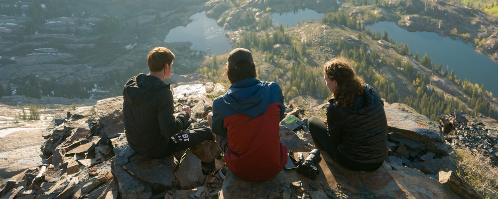 Tre kompisar sitter på ett berg