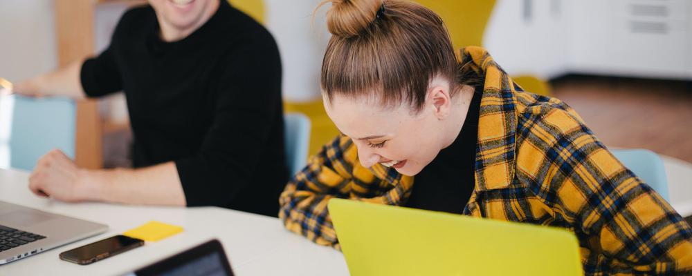 Young woman laughing in at her desk.