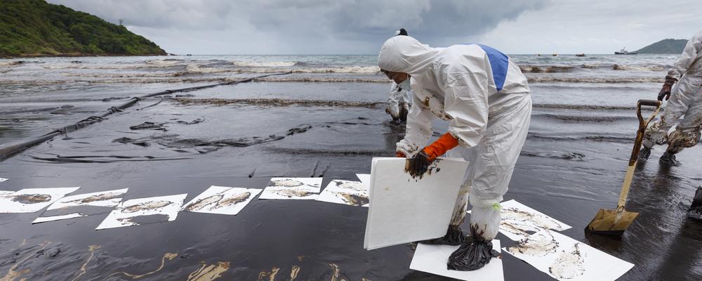 En man sanerar oljeutsläpp på en strand