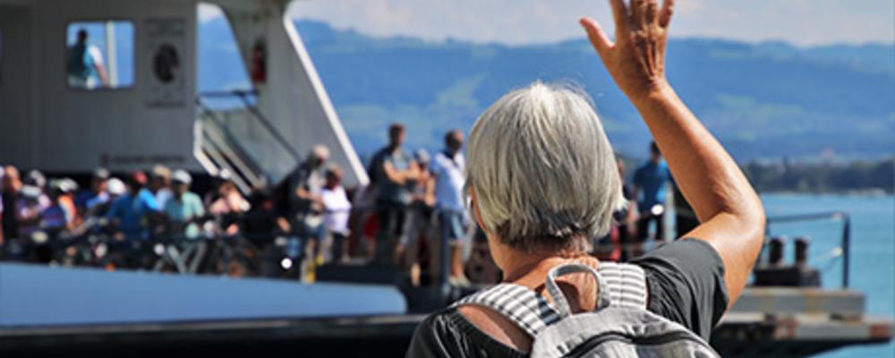 Äldre person vinkar av en färja