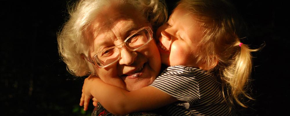 Äldre kvinna får en kram av en liten flicka