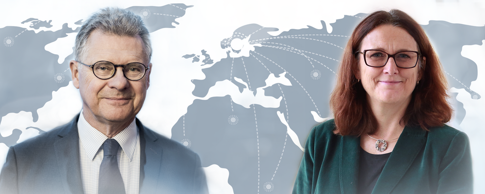 Klas Eklund & Cecilia Malmström ståendes mot varandra med en världskarta emellan dem 