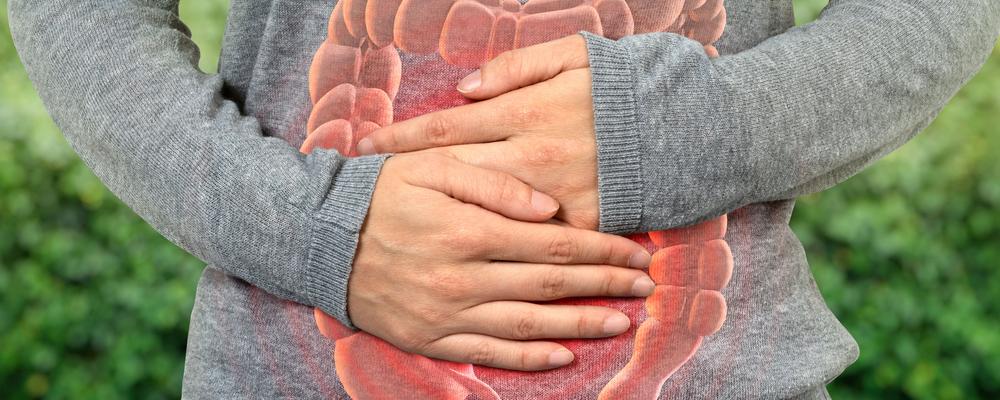 En person håller händerna över magen för att visa obehagskänslor över smärta.