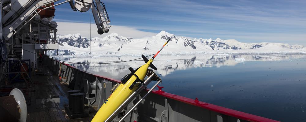 Mätinstrument står på däck på forskningsfartyg framför isberg på Antarktis. 
