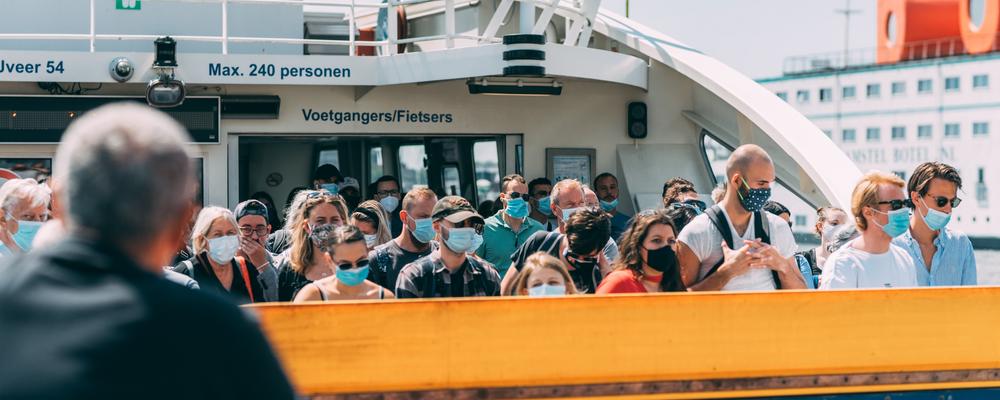 Folksamling med munskydd ombord på en färja under corona-pandemin