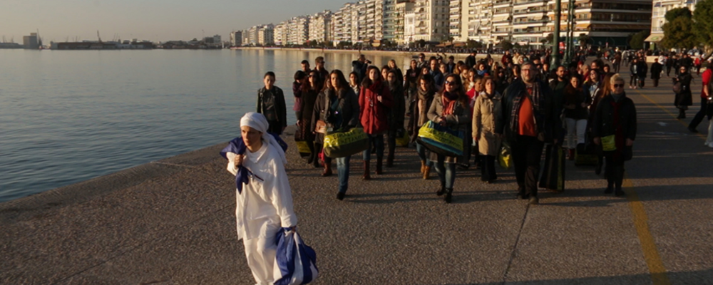En folksamling vandrar längs en hamn vid Medelhavet