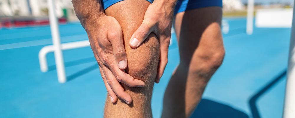 En friidrottare håller om ett smärtande knä.