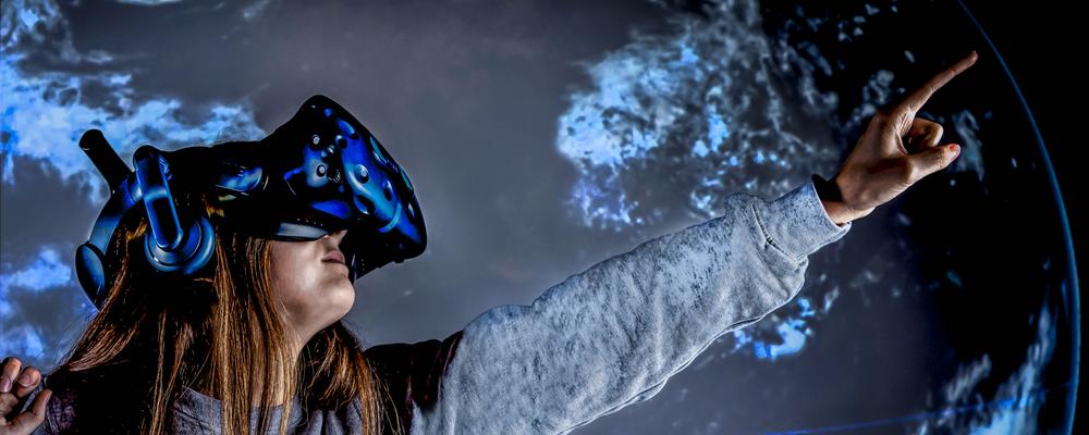 En flicka med ett par avancerade 3D-glasögon pekar ut mot rymden.