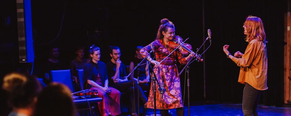 A violinist and singer play together on stage.