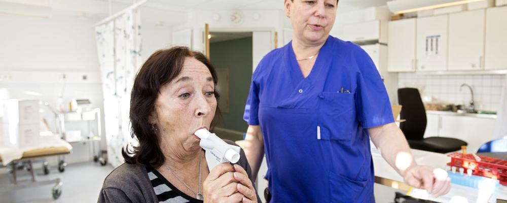 Kvinna genomför ett utandningstest under överssende av en forskningssjuksköterska